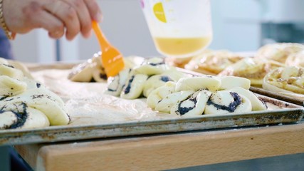 Baker lubricating the top surface of sweet baking before input into oven
