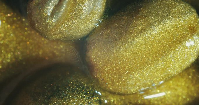 Coffee beans in gold oil.  gold oil paints. Macro. 4K.
