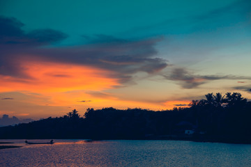 Obraz premium Colorful sky sunset with cloud above silhouettes of trees at riverside.