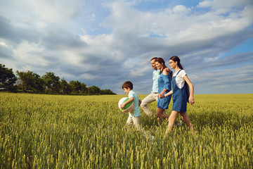 Happy family walking in summer field.