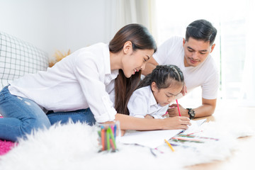 Young family drawing together with colorful pencils at home,Asian kids and happy people concept.kid girl drawing with color pencils,Hand of asian child draw and paint with crayon in vintage color tone