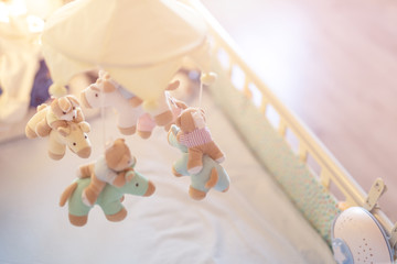 Close-up baby crib with musical animal mobile at nursery room. Hanged developing toy with plush fluffy animals. Happy parenting and childhood, expectation delivery of a child concept - obrazy, fototapety, plakaty