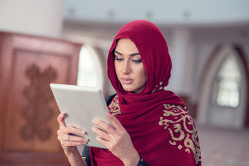 Beautiful young woman with tablet computer inside mosque