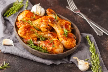 Gartenposter Grilled spicy chicken legs baked with garlic, rosemary and thyme on dark background. © vaaseenaa