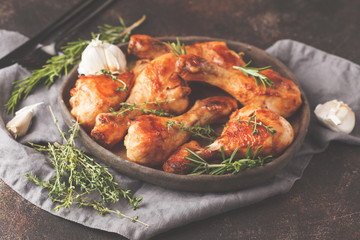 Grilled spicy chicken legs baked with garlic, rosemary and thyme on dark background.