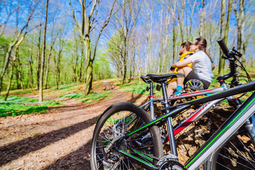 couple sit on stump resting after cycling by forest