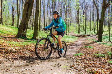 Fototapeta na wymiar young woman ride bicycle in forest by trail