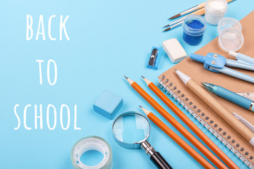 School stationary on blue background with inscription BackTo School. Notebook, pens, pencils and other tools.