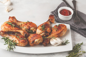 Grilled spicy chicken legs baked with garlic, rosemary and thyme on white background.