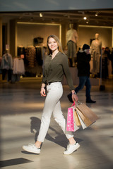 smiling young woman with shopping bags over mall background
