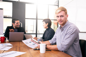 Fototapeta premium Businessman looking to camera with attractive smile. People working at office place together.