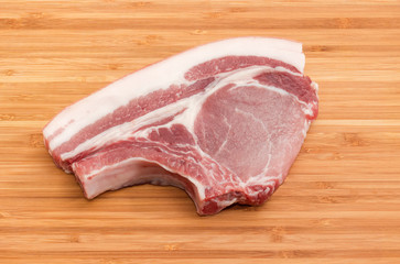 Uncooked pork loin chop bone on the bamboo cutting board