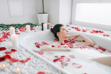 Attractive lady lying in bath with rose petals - Powered by Adobe