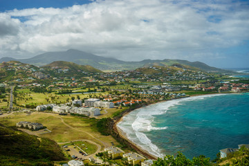 Fototapeta na wymiar A view over St. Kitts Island with residential area and beaces on the foreground and lush green hills on the background
