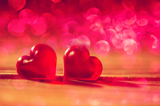 Red little decorative hearts on wooden background with amazing bokeh lights. Love or romantic Valentine day concept. Toned.