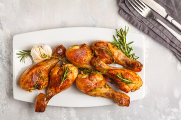 Grilled spicy chicken legs baked with garlic, rosemary and thyme on white background.