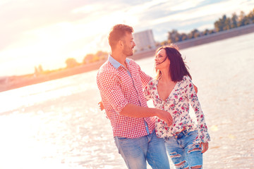 Happy young couple laughing and hugging on the beach.