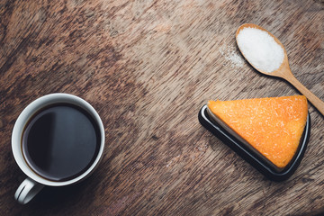 Cup of hot black  coffee and cake  powdered sugar on wooden table. top view
