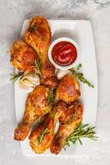 Grilled spicy chicken legs baked with garlic, rosemary and thyme on white background.