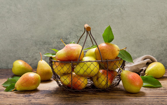 pears with leaves in a basket on wooden table
