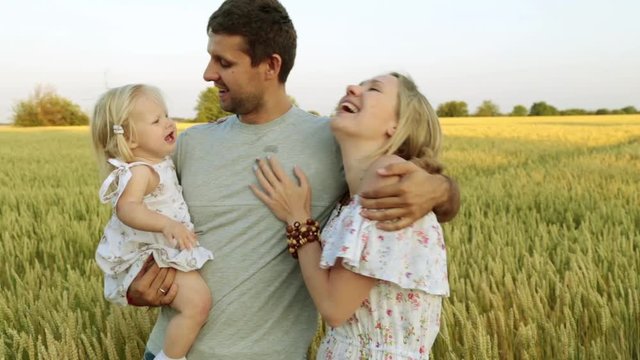 Young family with a child in the background of a wheat field.