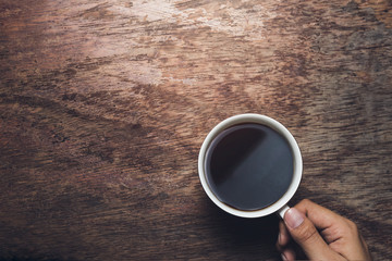 Male hand hold mug of espresso coffee on vintage wood table. - 210627364
