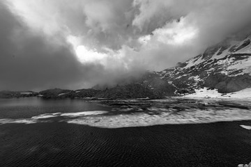 Obraz premium Czarno-białe zdjęcie alpejskiego jeziora w odwilży