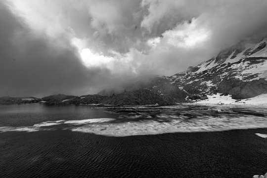 Black and white photo of an alpine lake at the thaw