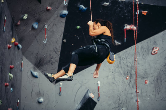 Active happy woman overhanging on tightrope in the training climbing center, climbing sport, mountaineering adventure.