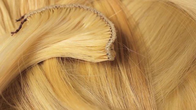 Hair extension cutted hair fibers blonde weft rotating pattern macro texture background backdrop footage video.