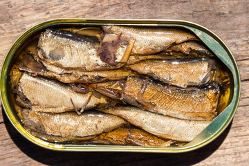 Open tin can of sprats on rustic wooden table