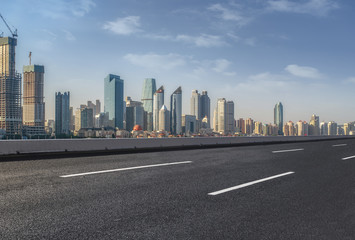 The empty asphalt road is built along modern commercial buildings in China's cities.