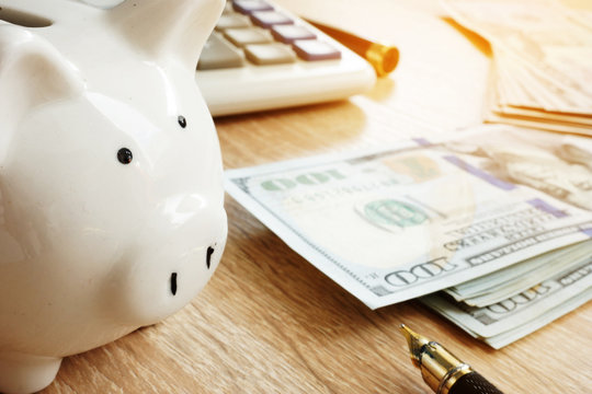 Savings. Piggy bank, calculator and money on a desk.