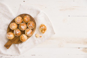Top view on Woooden board with himemade vanilla muffins on white background. Baking at home