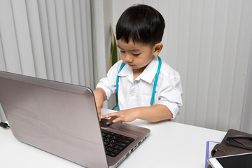 Little boy in medic uniform using a laptop on desk