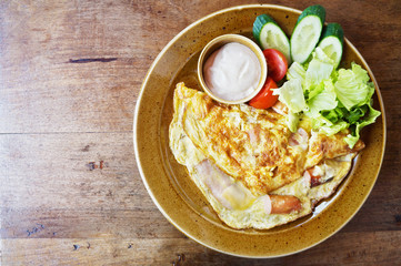 Omelette or scrambled eggs with bacon, cheese and fresh vegetables, top view with space for text               
