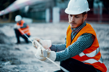 Worker in orange uniform and white helmet. Safety during roadworks