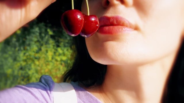 Beautiful young woman eating sweet cherries close-up shot