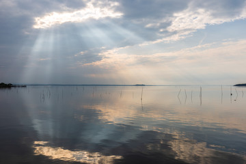 Perfectly symmetric and spectacular view of a lake, with clouds, sky and sun rays reflecting on water