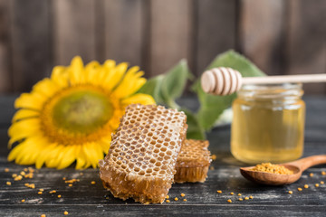 Beautiful transparent honey in bank, honeycombs and pollen on a wooden table. It can be used as a background