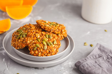 Fresh oatmeal pumpkin cookies on a gray plate, halloween food, autumn food, vegan food concept.