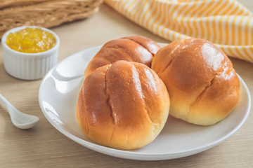Round bun, bread rolls on white plate and pineapple jam