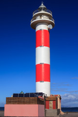 Lighthouse on beach against blue sky