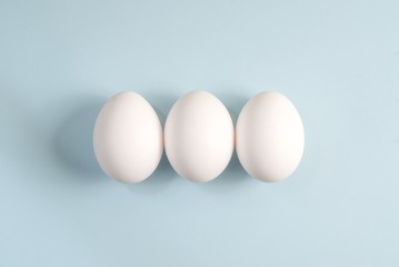 Three white eggs on a blue background
