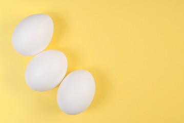 Three white eggs on a yellow background