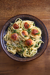 Pasta with meatballs and spinach. Spaghetti with meatballs in bowl on wooden table. overhead, vertical