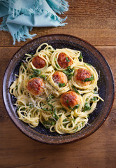Pasta with meatballs and spinach. Spaghetti with meatballs in bowl on wooden table. overhead, vertical