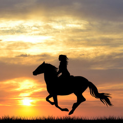 Black silhouette of a woman riding a horse at sunrise © hibrida