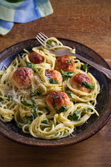 Pasta with meatballs and spinach. Spaghetti with meatballs in bowl on wooden table. vertical