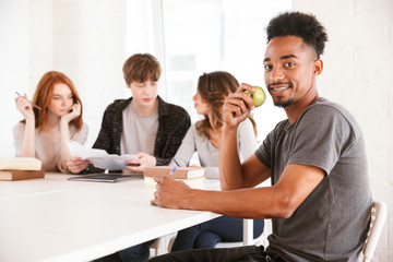 African guy holding apple looking camera